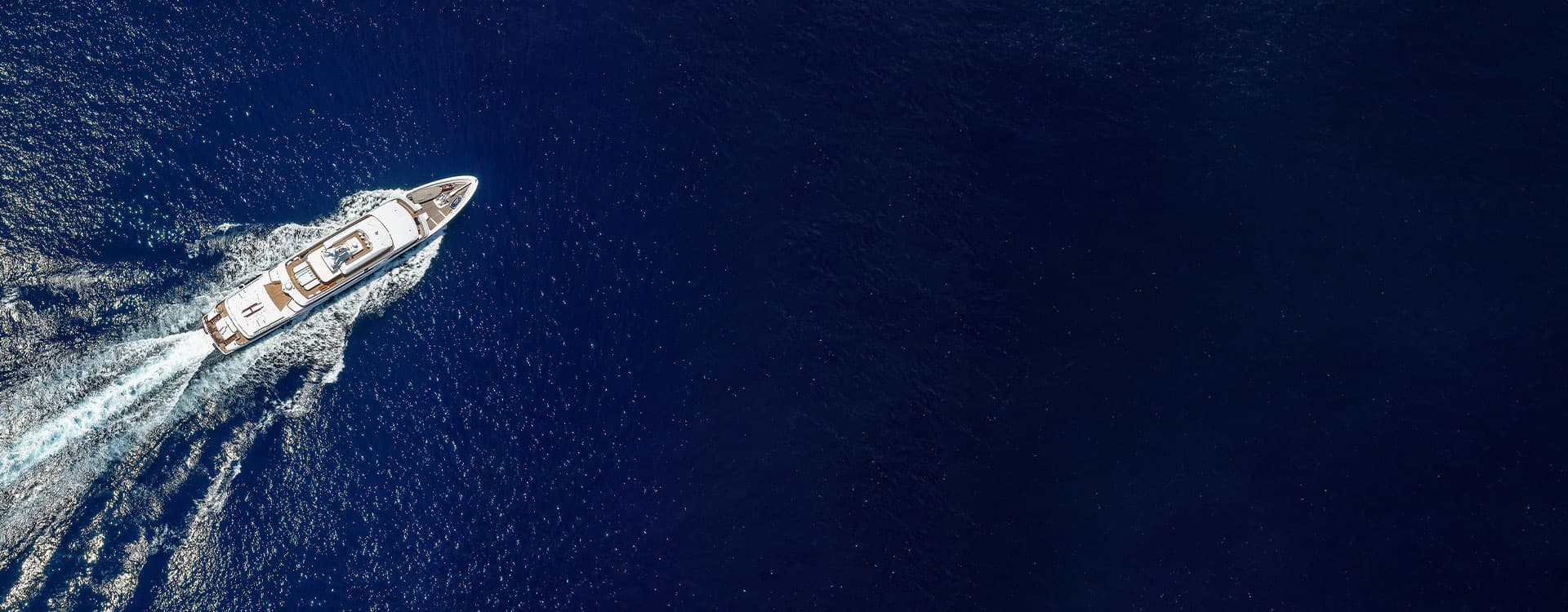 Aerial view of a luxury yacht cruising through deep blue ocean waters