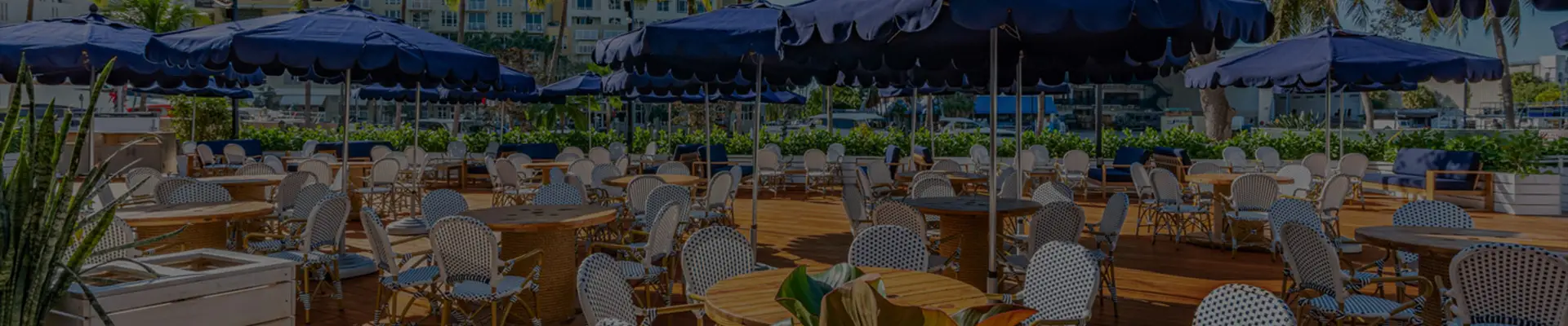 The Wharf Fort Lauderdale outdoor waterfront deck with navy umbrellas and bistro seating